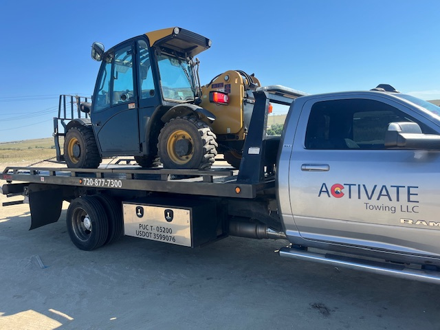 Activate Towing flatbed hauling a JCB telehandler — medium-duty equipment transport in Colorado